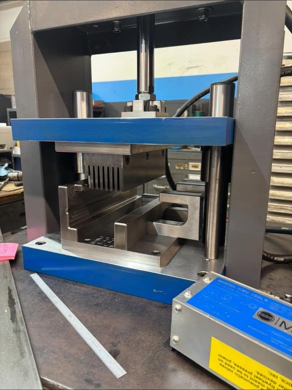 A forming die set up between the platens of a press on the shop floor.